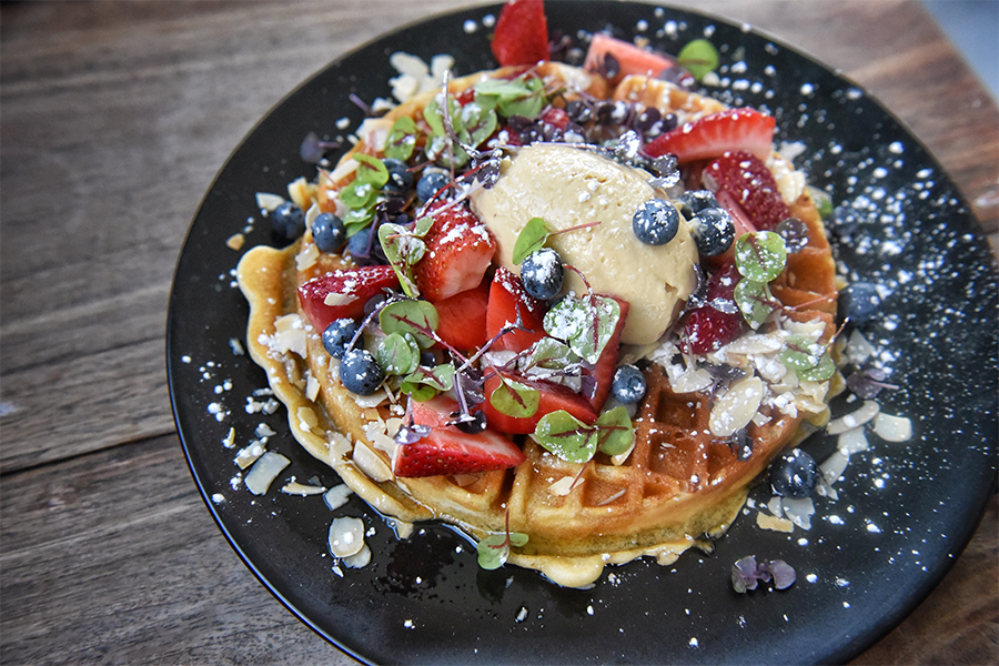 A golden waffle dressed with fresh fruit and yoghurt